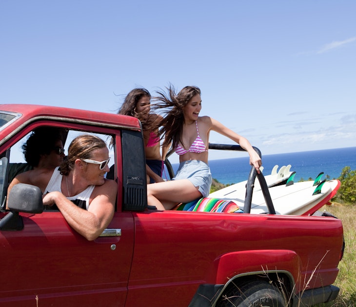 Four people in a red truck drive off road in Puerto Rico.